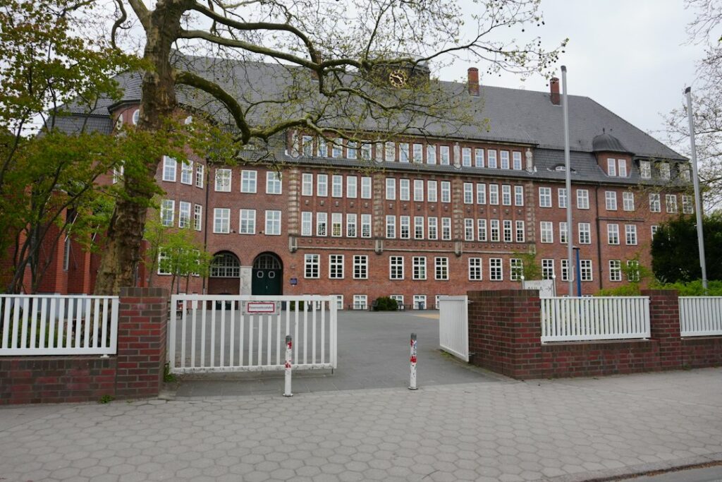 Large brick school-style building with trees and an open gate